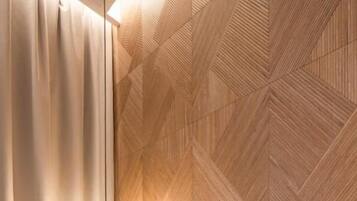 A modern bedroom with a geometric-patterned headboard, a bedside table, and a hanging light fixture.