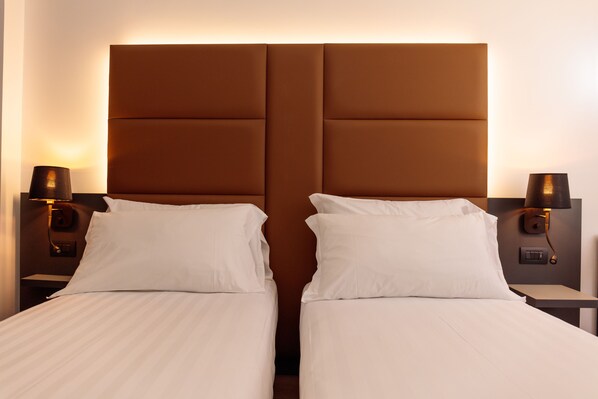 A hotel room with two beds, a brown headboard, and bedside lamps. - London Hotel (Milan)