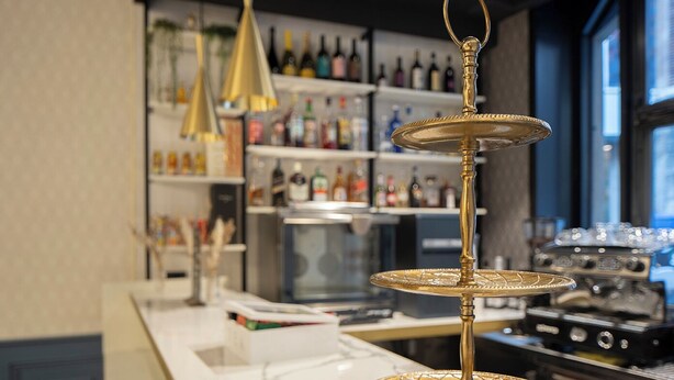 Un espace bar équipé d’un mini-bar, d’étagères remplies de bouteilles d’alcool et d’une machine à café.