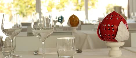 A dining table set with wine glasses, a small glass, a red decorative item, and a white napkin.