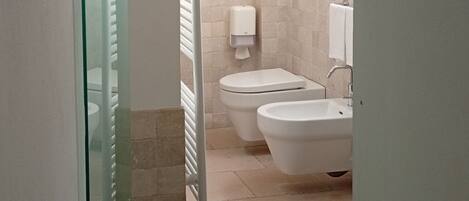 A bathroom with a toilet, bidet, and sink.