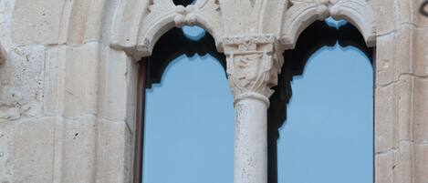 A stone window with a lion statue, Gothic arches, and a blue glass pane.