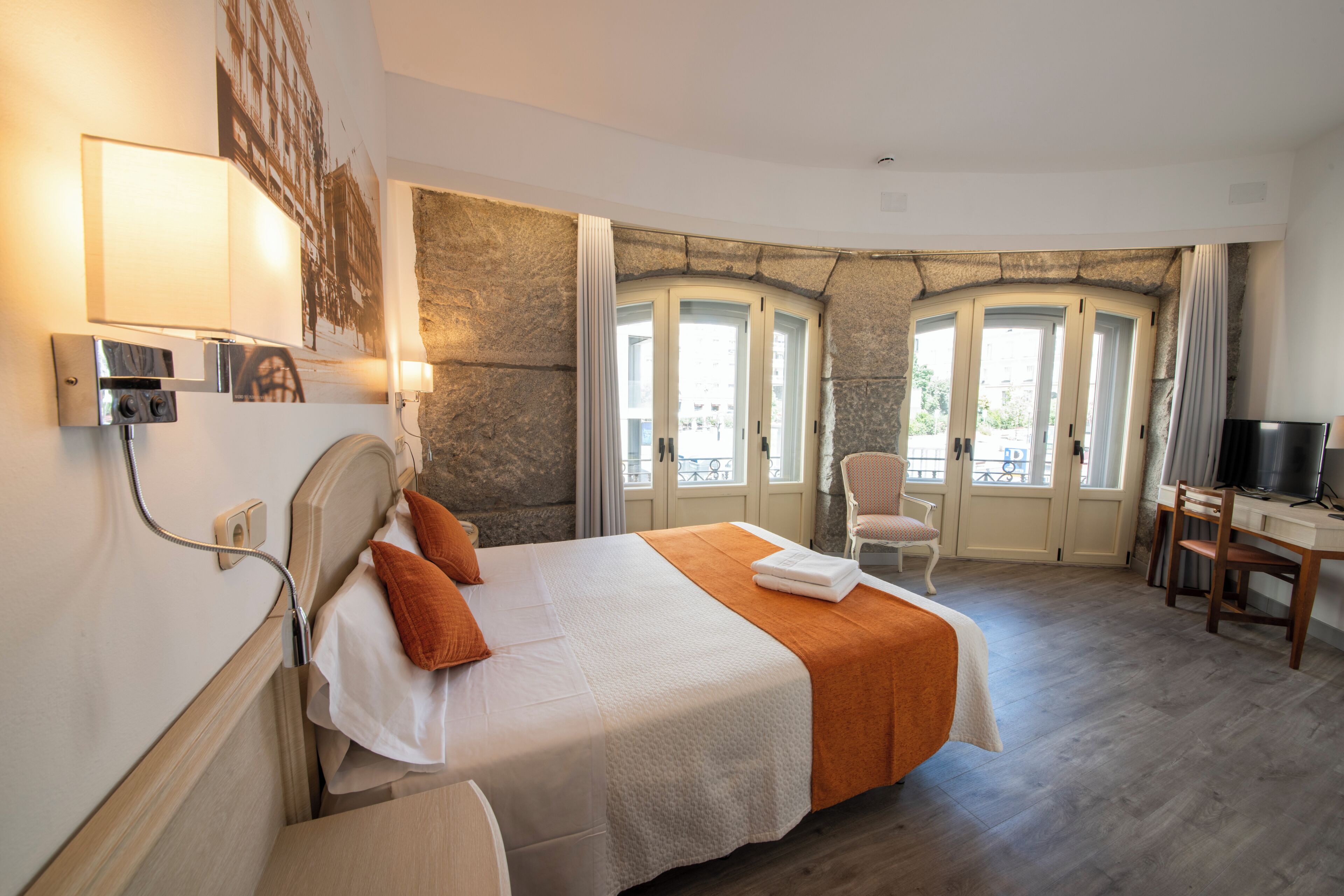 Ein Hotelzimmer mit Bett, Schreibtisch, Sessel und Fernseher.