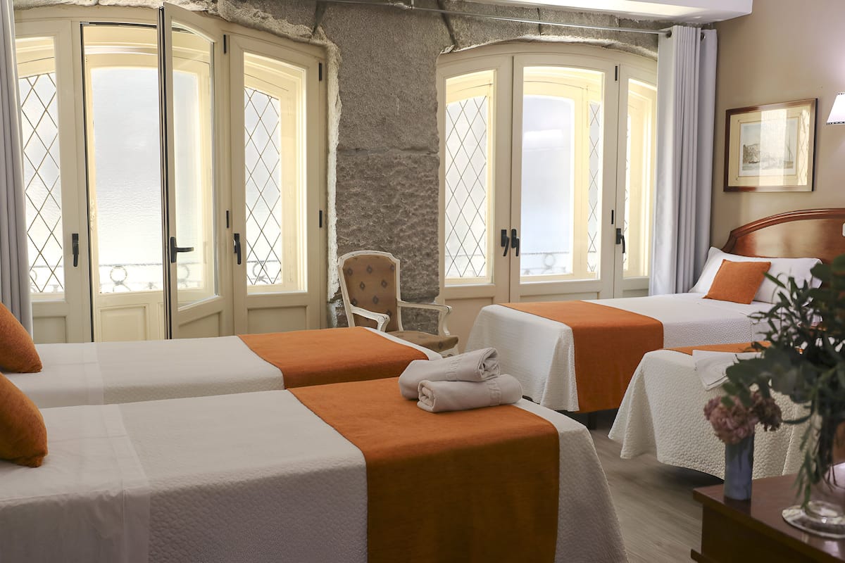 Ein Hotelzimmer mit zwei Betten, einer Steinwand und Blick durch die Türen.