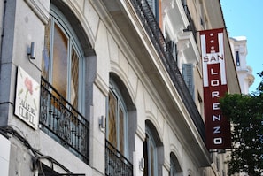 Fachada de edificio con un cartel que dice "Calle del Clavel" y un banderín de "San Lorenzo".