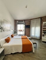 A hotel room with two beds, a brick wall, a large window, and a mounted TV.