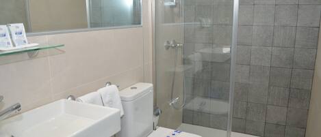 A bathroom with a white sink, toilet, and shower.