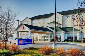 A Hilton Garden Inn hotel with a modern design, featuring a large entrance and a parking area.