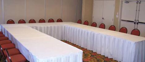 A conference room with a long table and red chairs.