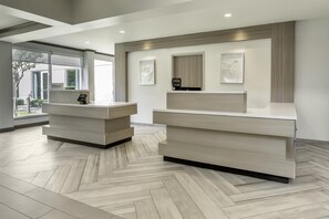 A reception desk area with two counters, a modern design, and a herringbone-patterned floor. - Hilton Garden Inn Houston/The Woodlands (The Woodlands)
