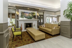 A modern living room with a fireplace, a flat-screen TV, and a sofa. - Hilton Garden Inn Houston/The Woodlands (The Woodlands)