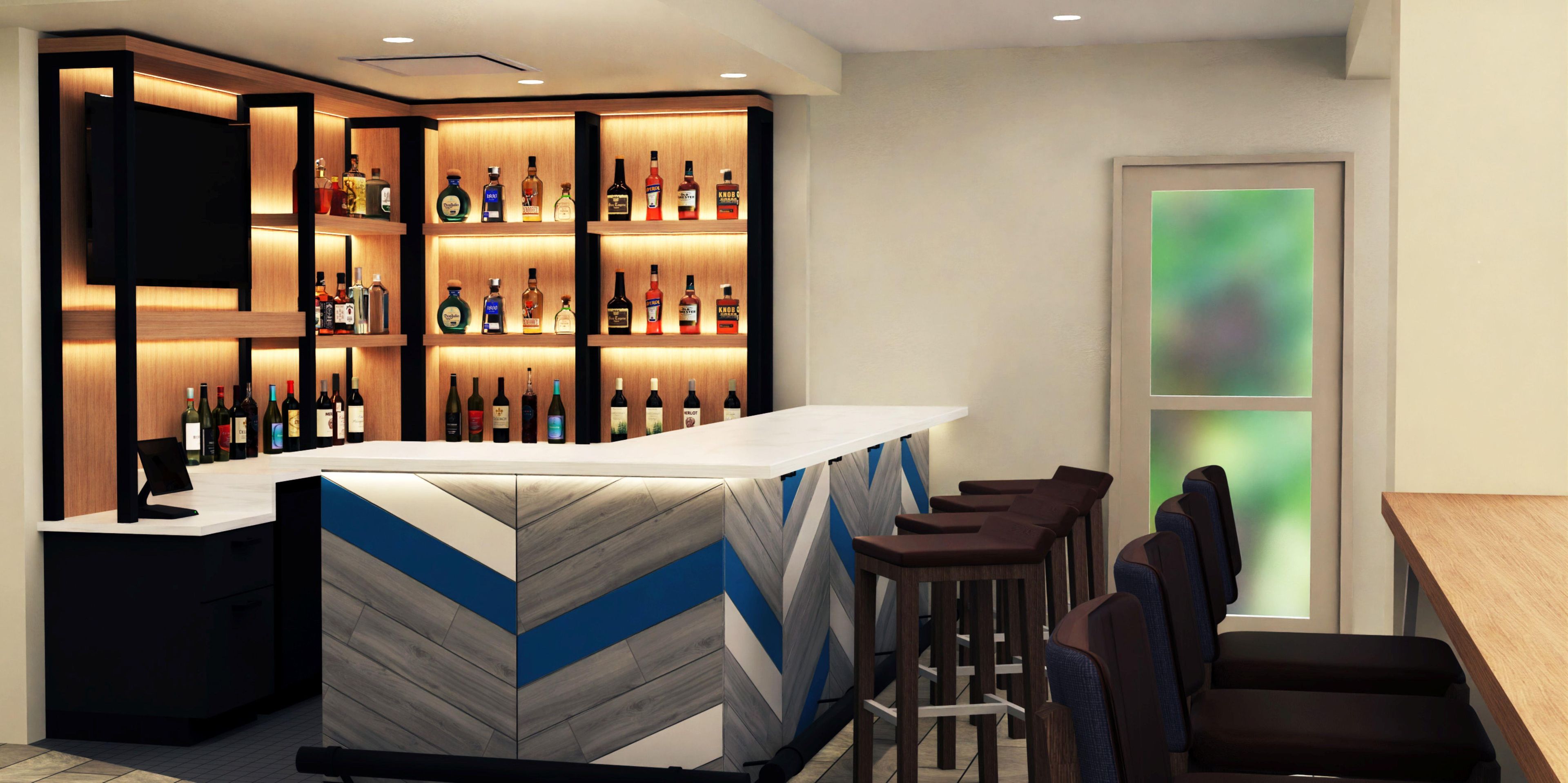Zona de bar con mostrador de madera, varias estanterías llenas de botellas de licor y taburetes.