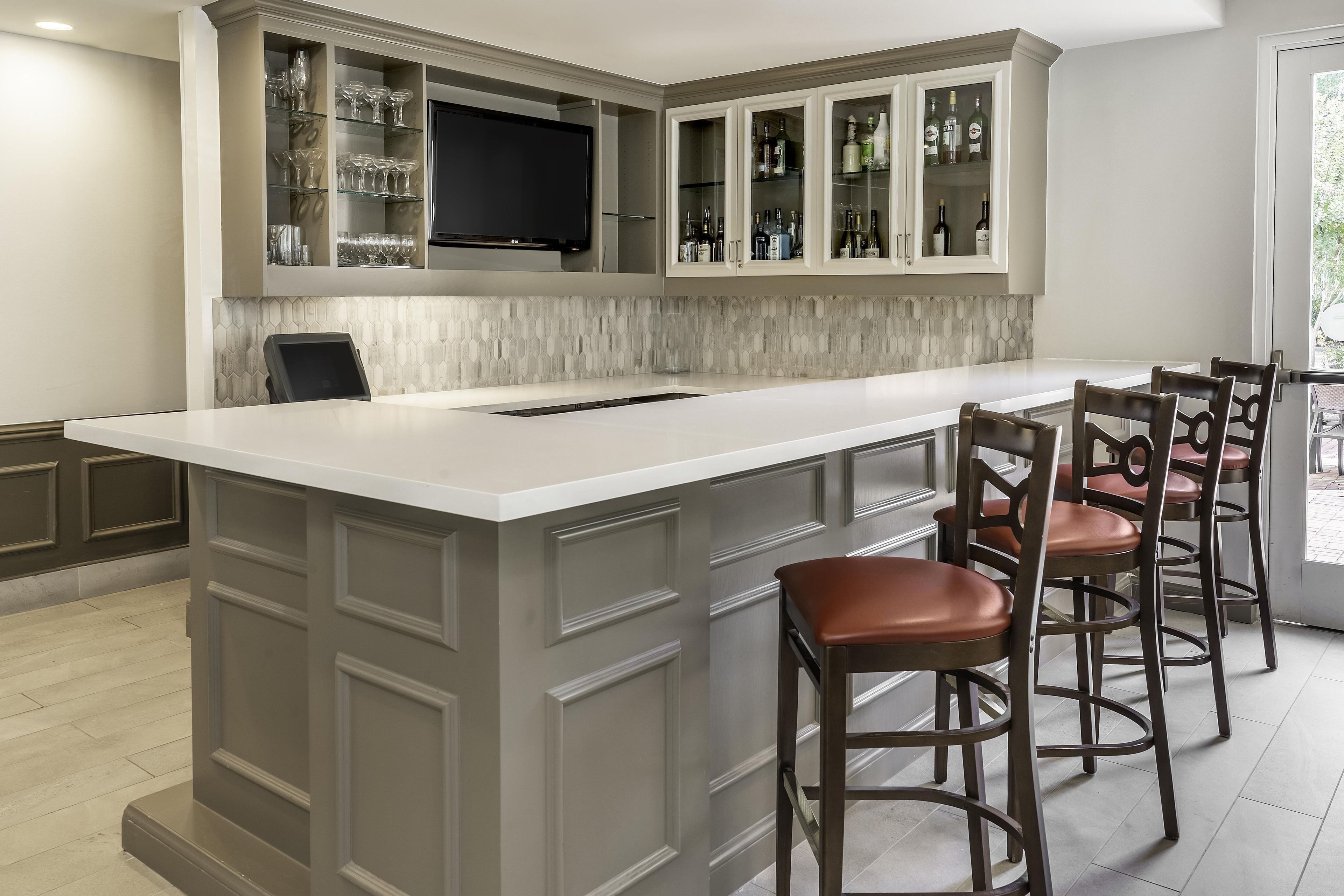 A kitchen with a large island, bar stools, and built-in cabinets.