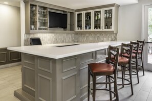 A kitchen with a large island, bar stools, and built-in cabinets. - Hilton Garden Inn Houston/The Woodlands (The Woodlands)