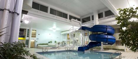 An indoor swimming pool with a blue water slide and a staircase leading to an upper level.
