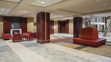 A lobby with a fireplace, red seating, and a staircase.