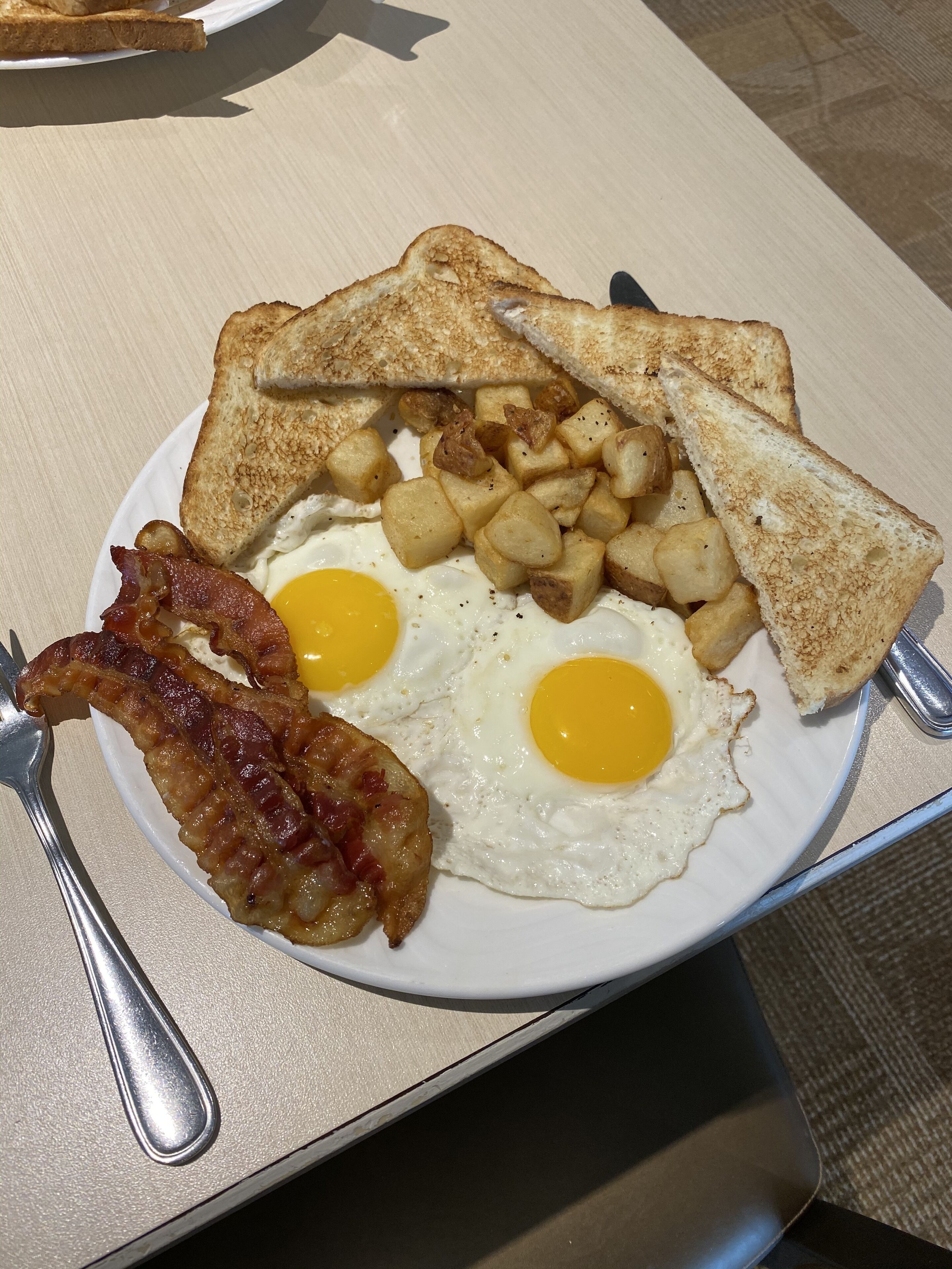A plate with toast, fried eggs, and bacon.