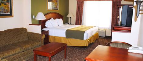 A hotel room with a bed, a sofa, a desk, and a chair.
