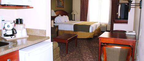 Une chambre d’hôtel équipée d’un lit, d’un bureau, d’une chaise, d’une machine à café et d’un téléphone.