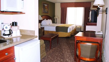 A hotel room with a bed, a desk, a chair, a coffee maker, and a telephone.