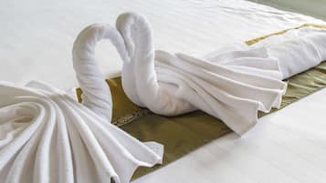 A neatly made bed with white towels folded into swan shapes and a gold pillow.