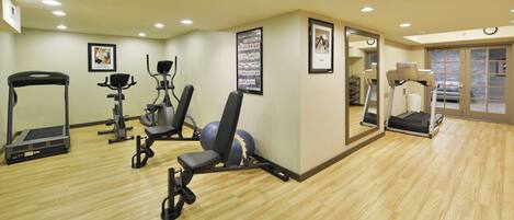 A gym with treadmills, stationary bikes, and exercise balls.
