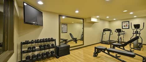 A gym with exercise equipment, a mirror, and a wall-mounted TV.