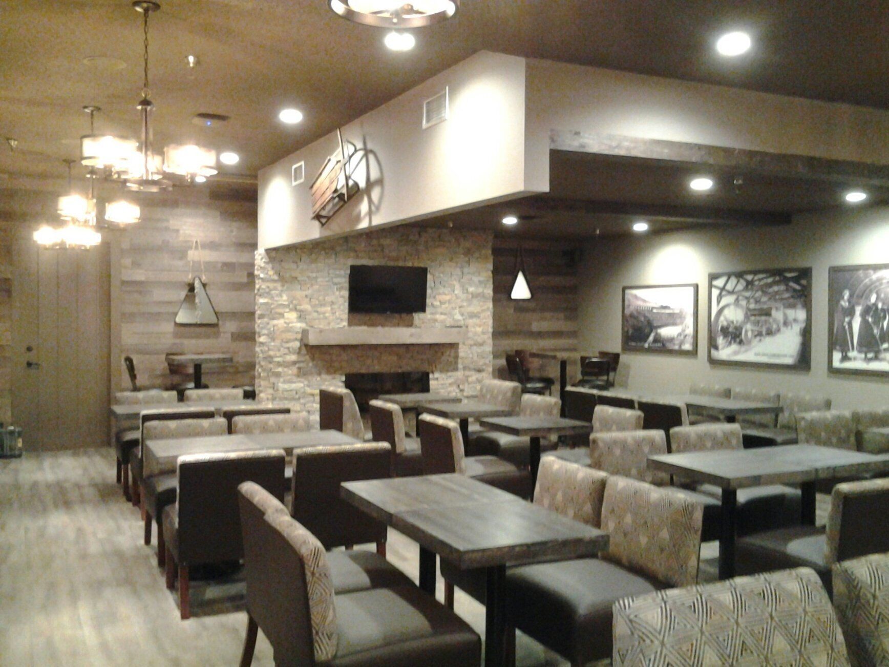 A restaurant with multiple tables and booths, stone walls, and a fireplace.