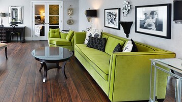 A living room with a green sofa, a glass coffee table, and a wooden floor.