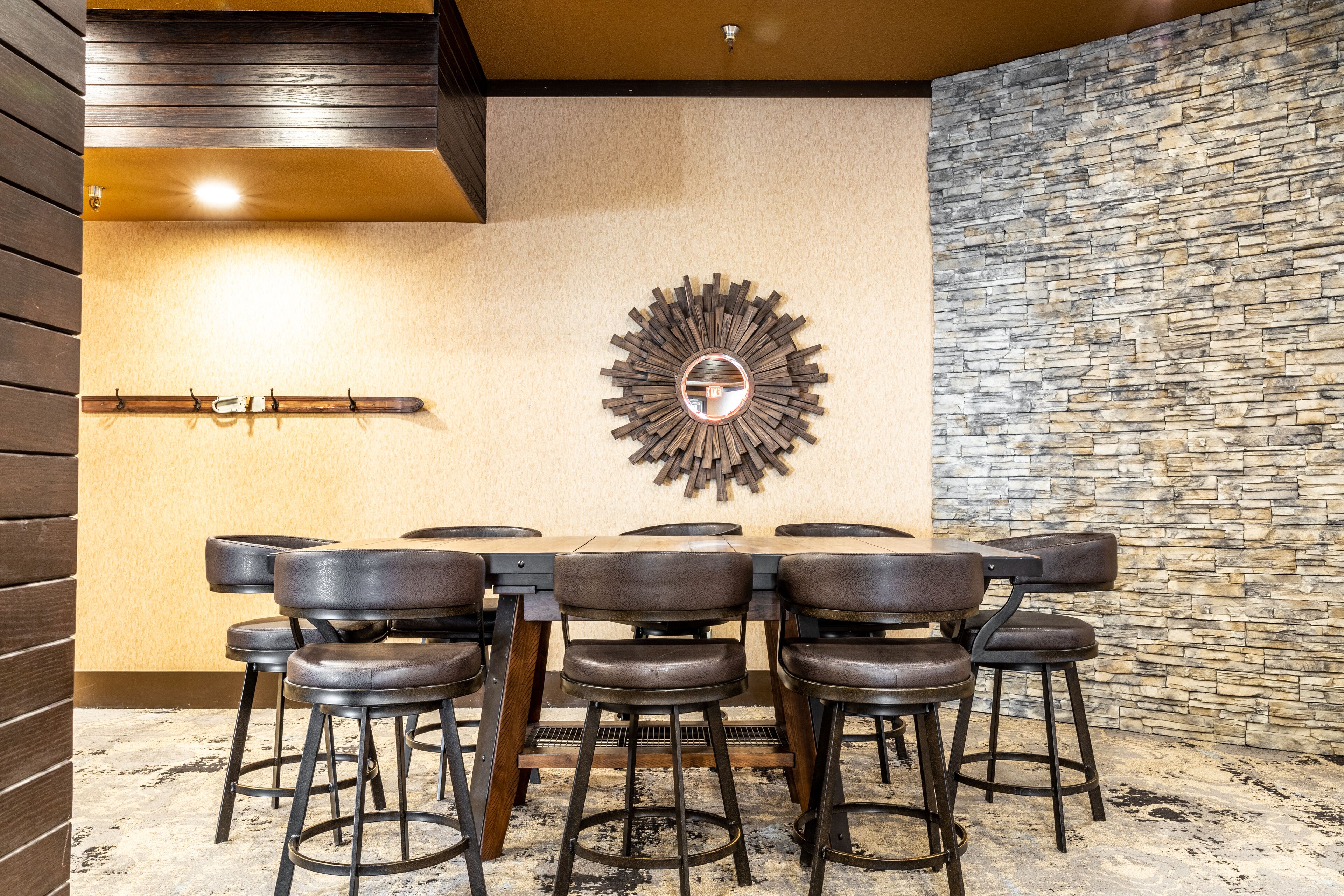 Un comedor con pared de piedra, techo de madera y un espejo redondo en la pared.