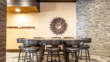 Un comedor con pared de piedra, techo de madera y un espejo redondo en la pared.