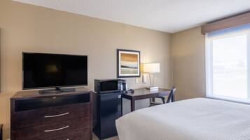A hotel room with a bed, a desk with a computer, a television, and a coffee maker.