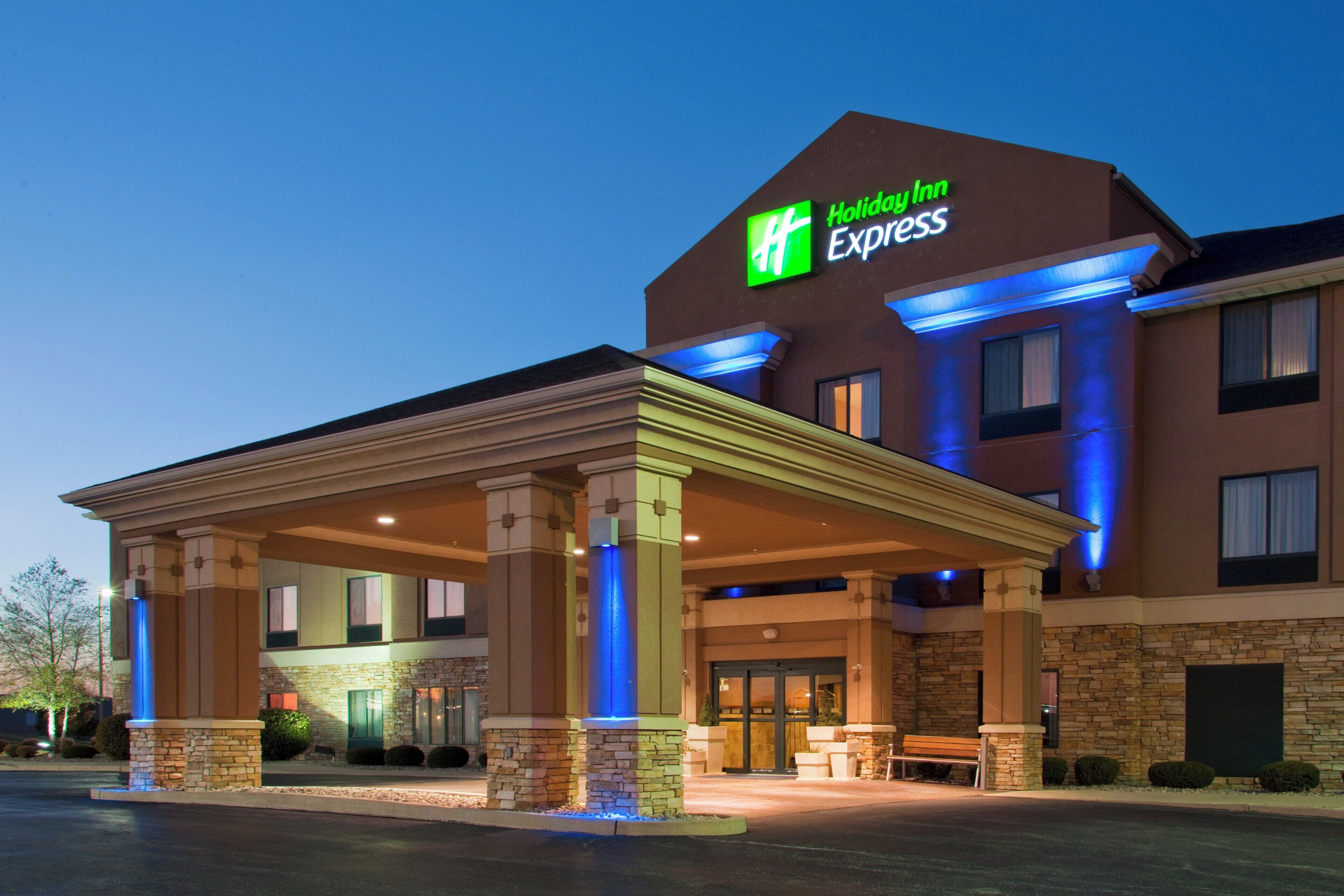 A Holiday Inn Express hotel with a covered entrance, stone facade, and illuminated signage.