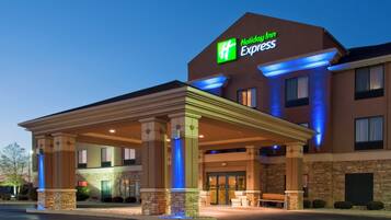 A Holiday Inn Express hotel with a covered entrance, stone facade, and illuminated signage.