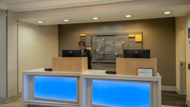 A reception desk with two HP computers, a Holiday Inn Express sign, and a sign for IHG One Rewards.