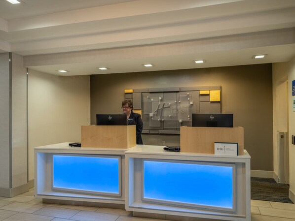 A reception desk with two HP computers, a Holiday Inn Express sign, and a sign for IHG One Rewards.