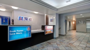 A reception area with a counter, informational posters, and a tiled floor. - Motel 6 Pharr, TX (Pharr)