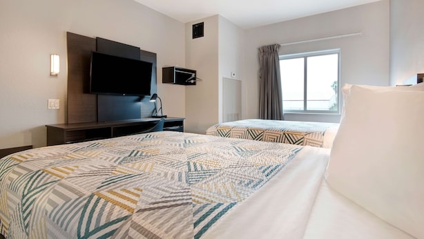 A hotel room with two beds, a flat-screen TV, a desk, and a window with curtains. - Motel 6 Pharr, TX (Pharr)