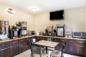 A compact kitchen with a dining area, equipped with a coffee machine, toaster, waffle maker, and a microwave. - Super 8 by Wyndham Phoenix Downtown (Phoenix)