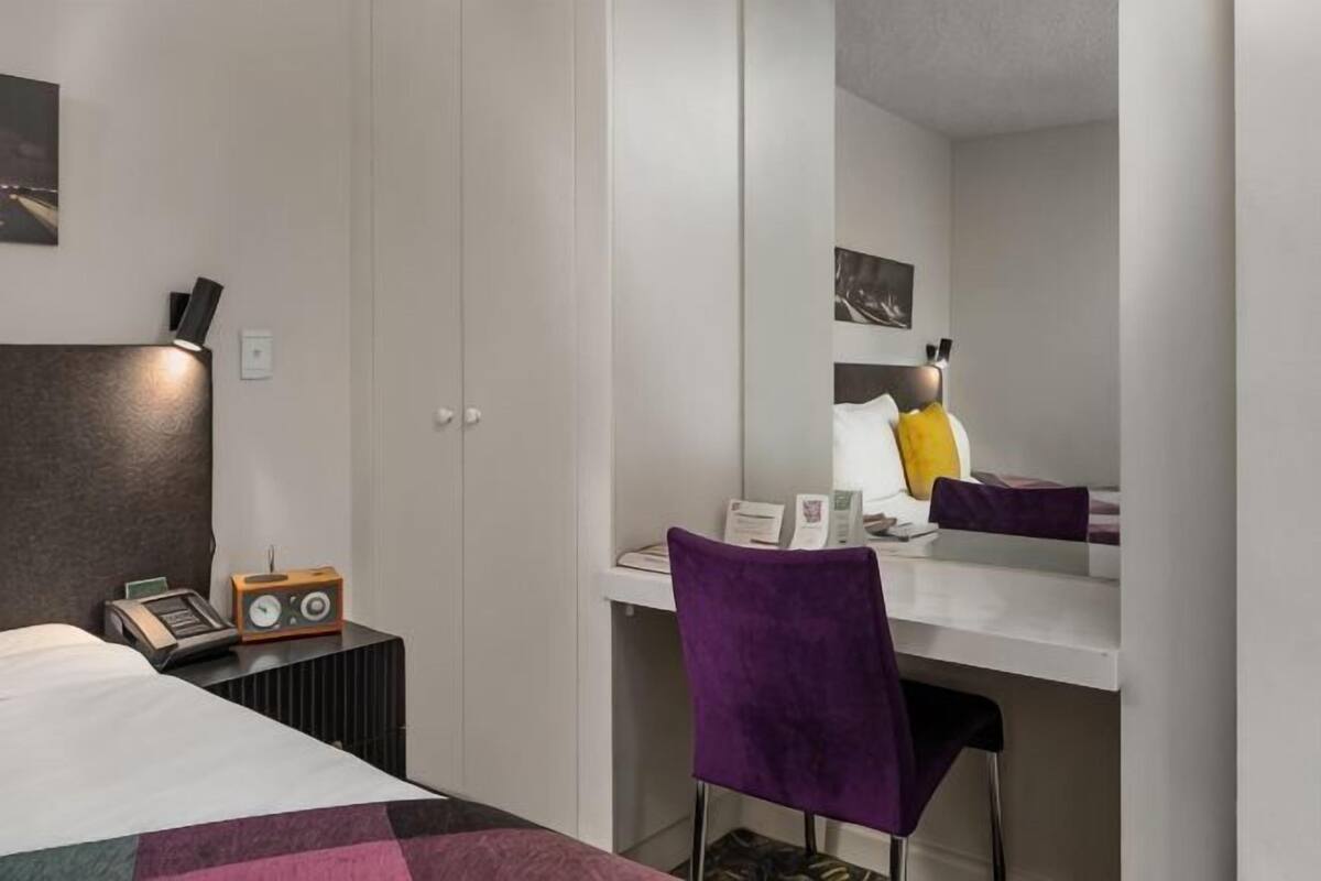 Un dormitorio con cama, escritorio, silla, armario y radio.