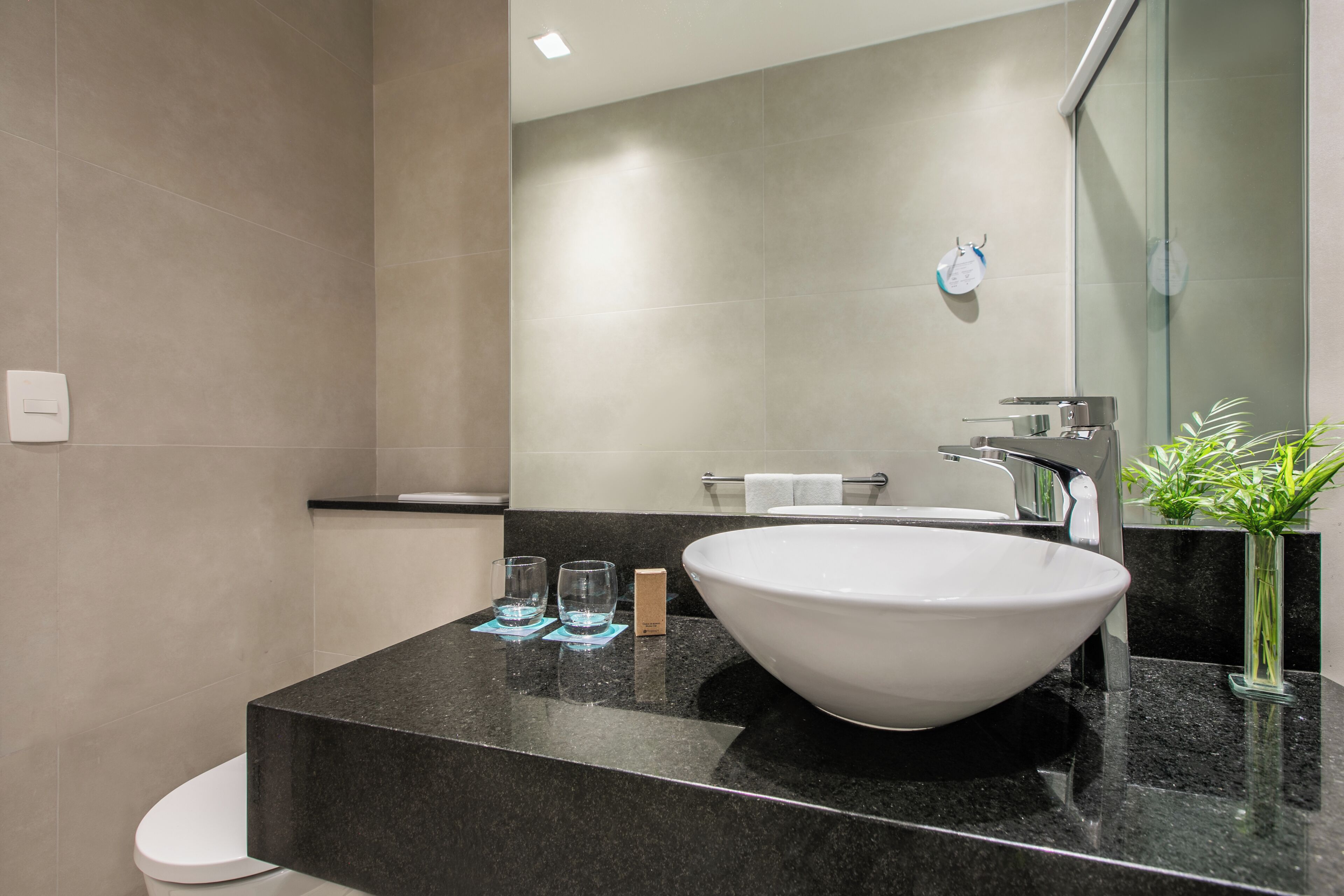 A modern bathroom with a large white sink, a mirror, and a glass shower enclosure.