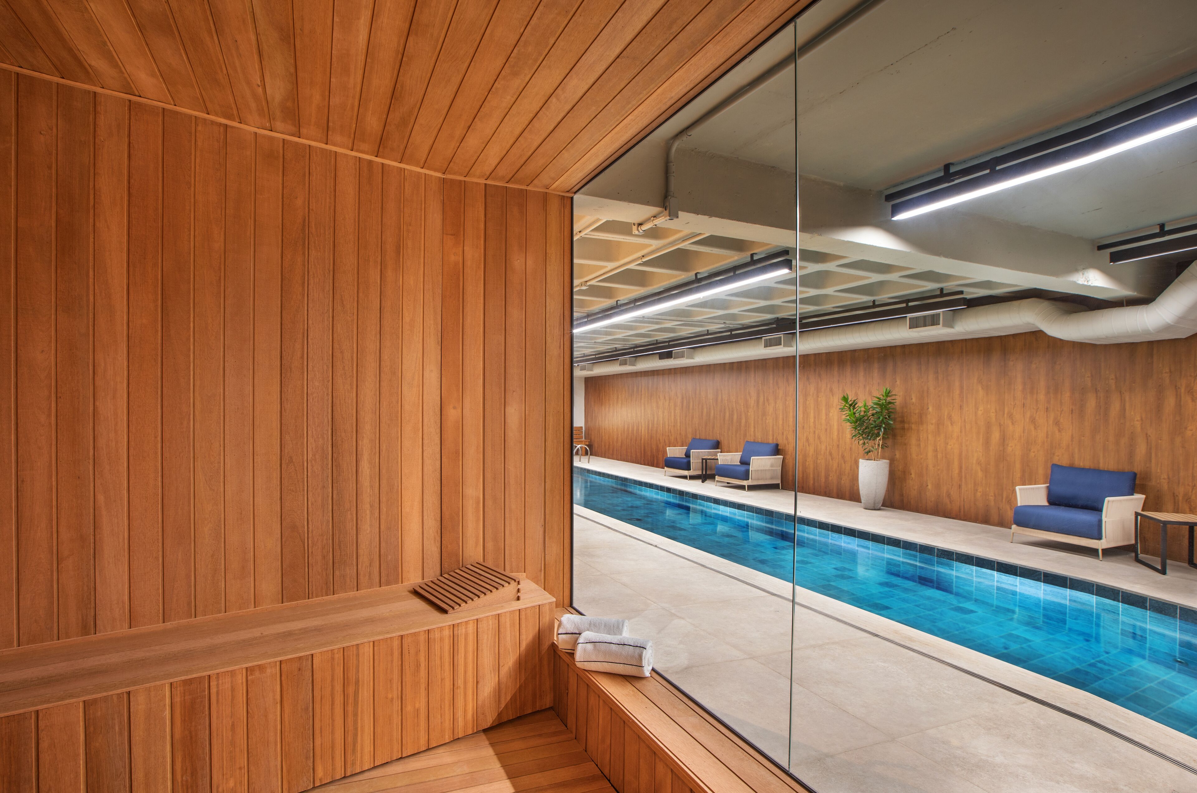A wooden sauna area with a view of a pool and seating area.