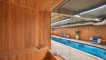 A wooden sauna area with a view of a pool and seating area.