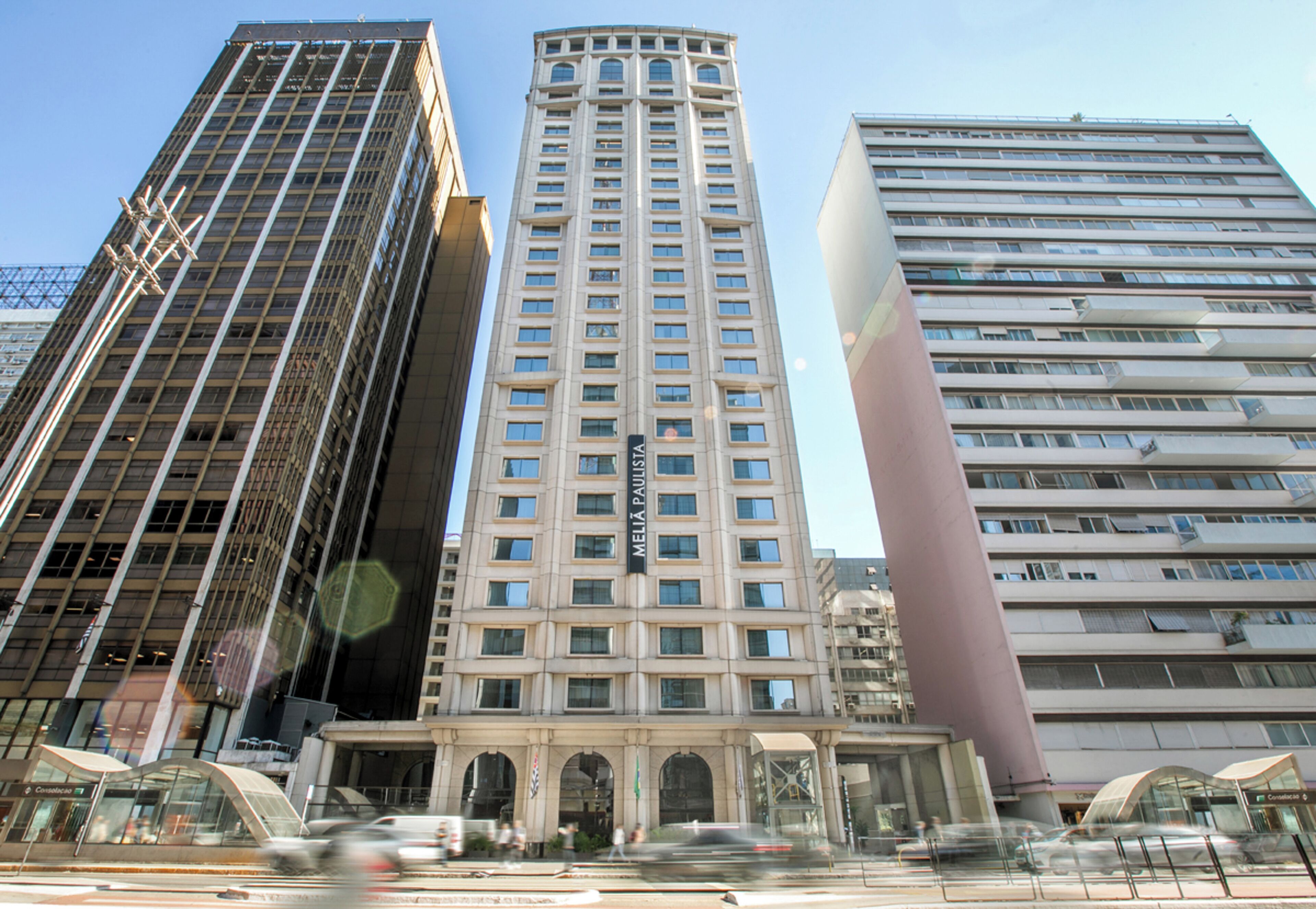 Um edifício alto e moderno com entrada destacada e fachada de vidro ampla.