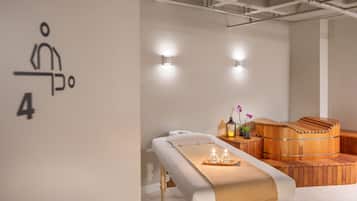 Un cuarto de spa con una camilla de masaje, una sauna de madera e iluminación empotrada.