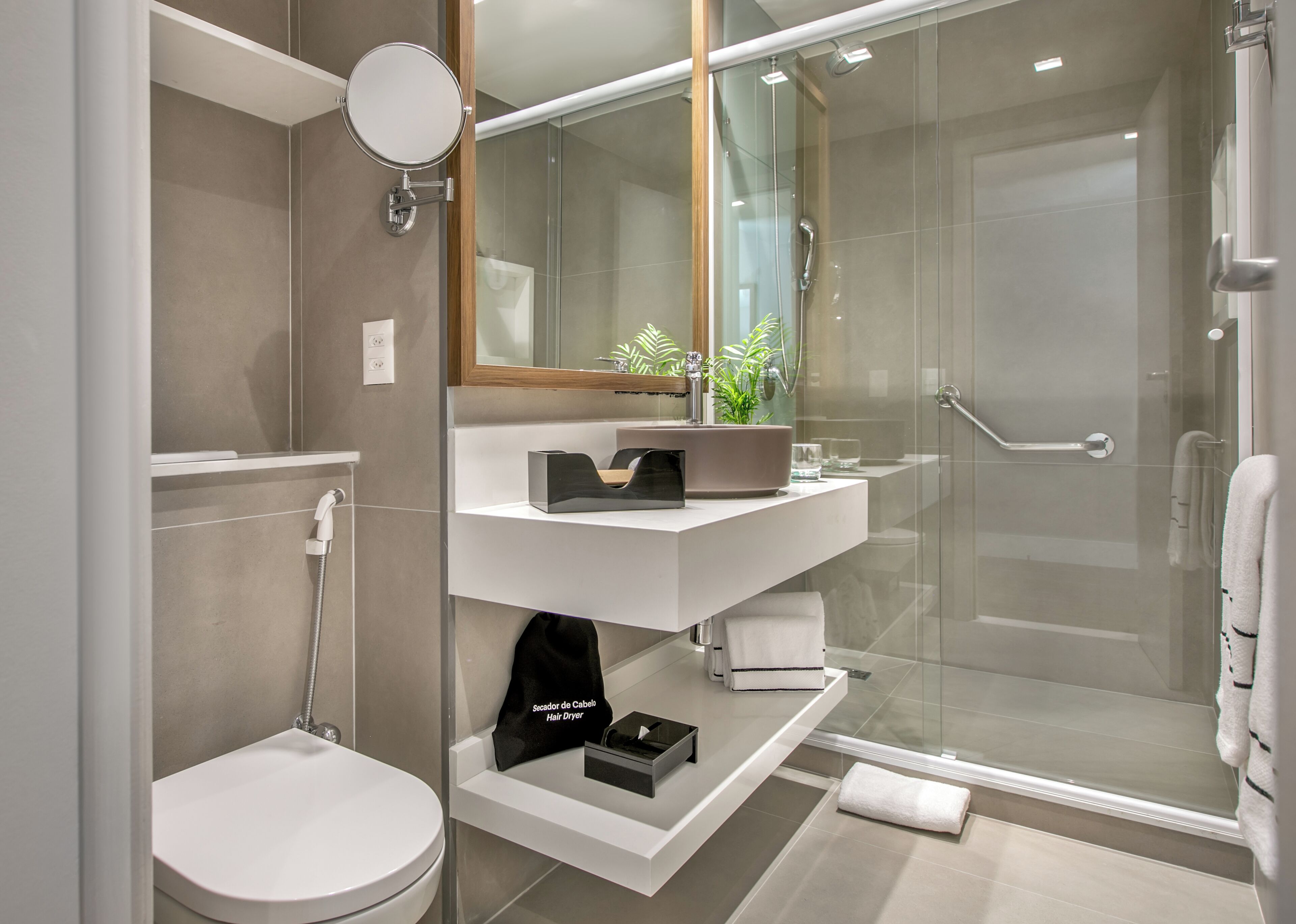 A modern bathroom with a glass-enclosed shower, a white sink, and a toilet.
