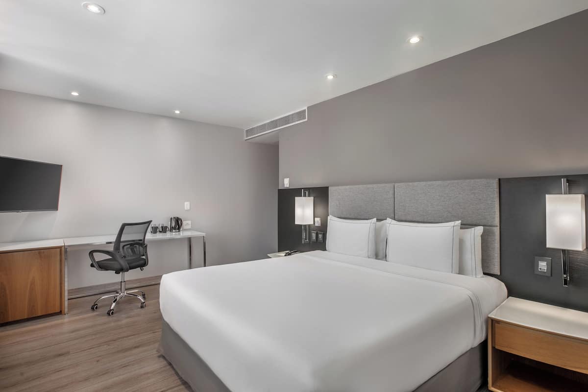 Una habitación de hotel moderna con una cama grande, un escritorio y una silla.