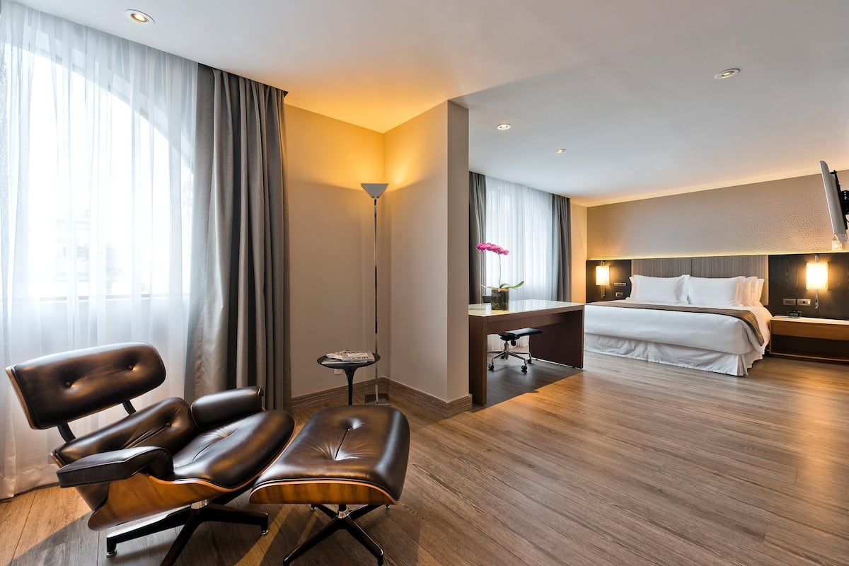 Una habitación de hotel con cama, escritorio, silla y lámpara.