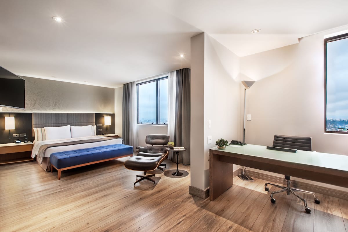 Una habitación de hotel moderna con una cama grande, un escritorio y vistas a la ciudad.