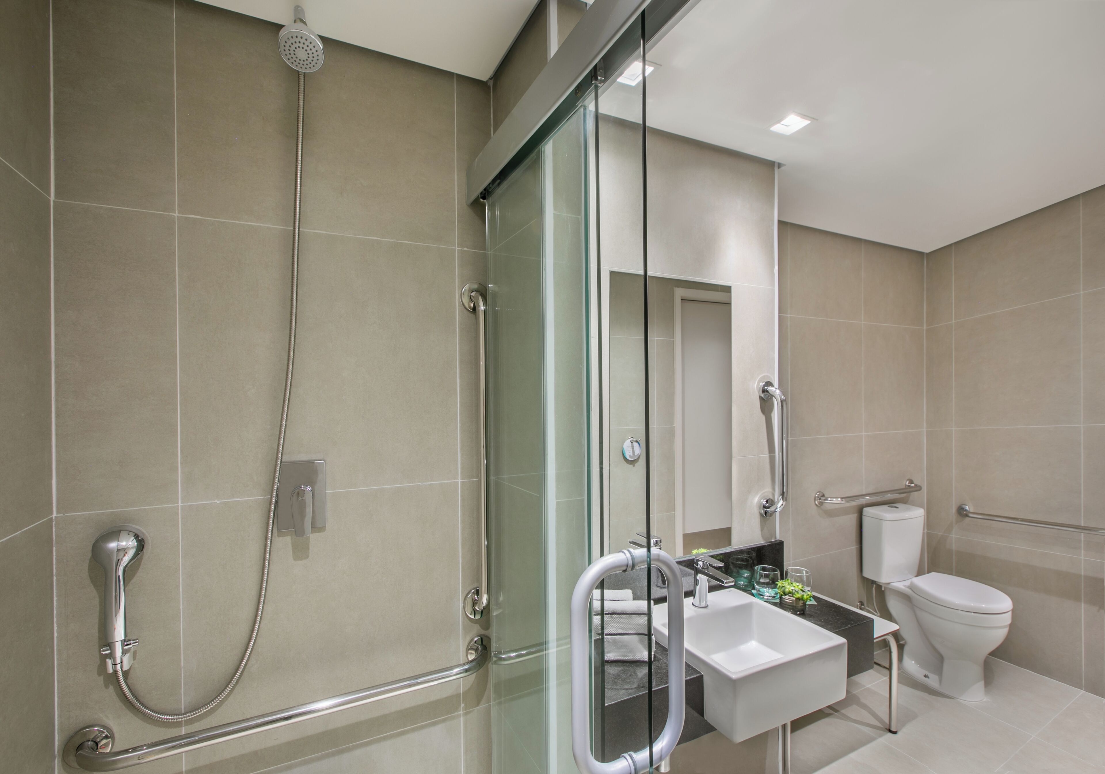 A modern bathroom with a glass-enclosed shower, a white sink, and a toilet.
